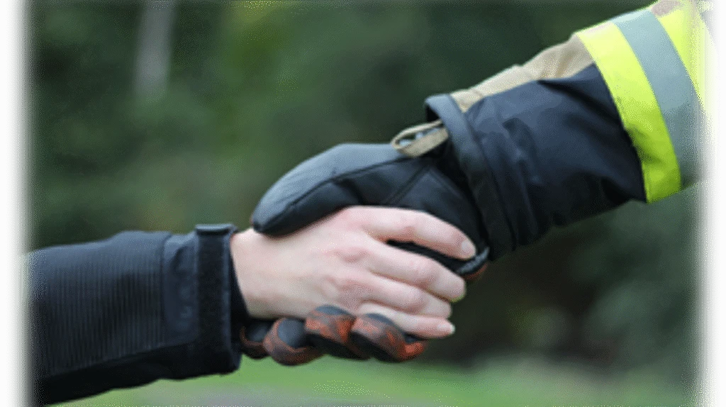 Räddningstjänstpersonal skakar hand med individ