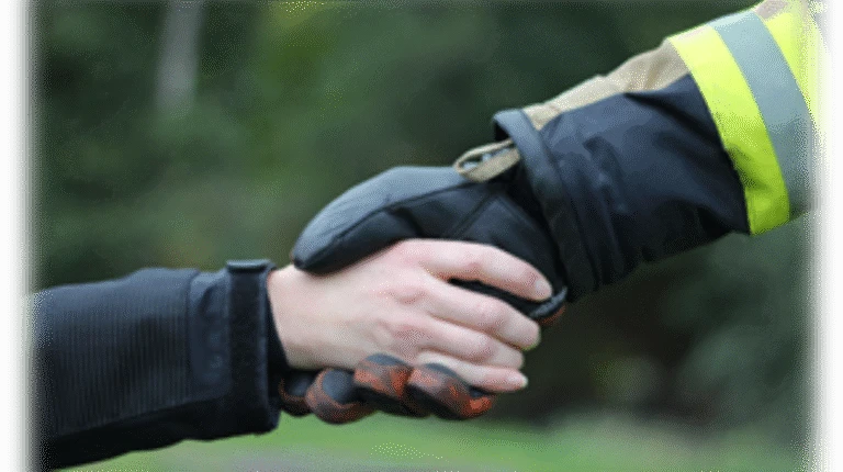 Räddningstjänstpersonal skakar hand med individ