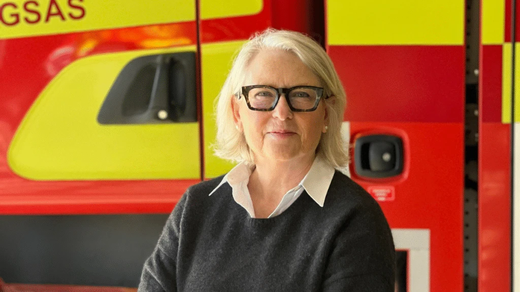 En kvinna poserar framför ett utryckningsfordon