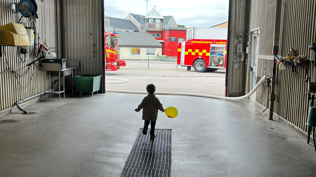 Ett barn leker i ett garage för utryckningsfordon