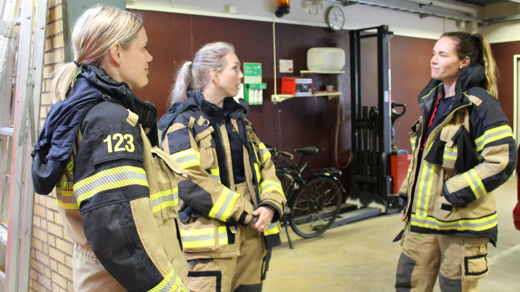 Kvinnlig utryckningspersonal i utrustning som diskuterar