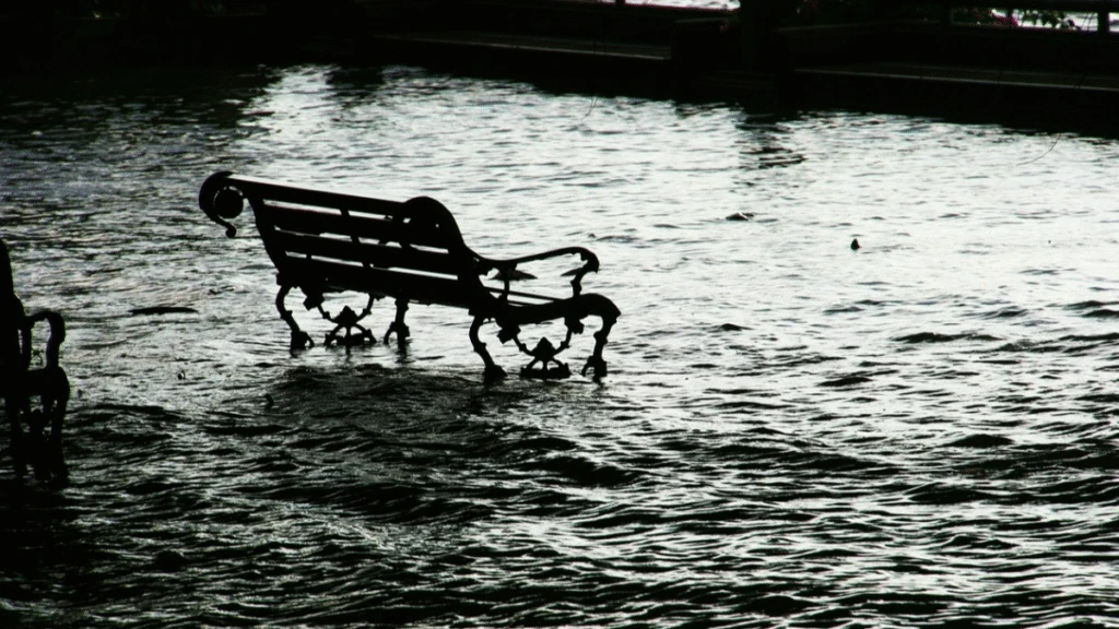 En parkbänk i högt vatten vid översvämning