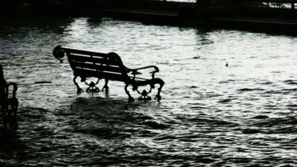 En parkbänk i högt vatten vid översvämning