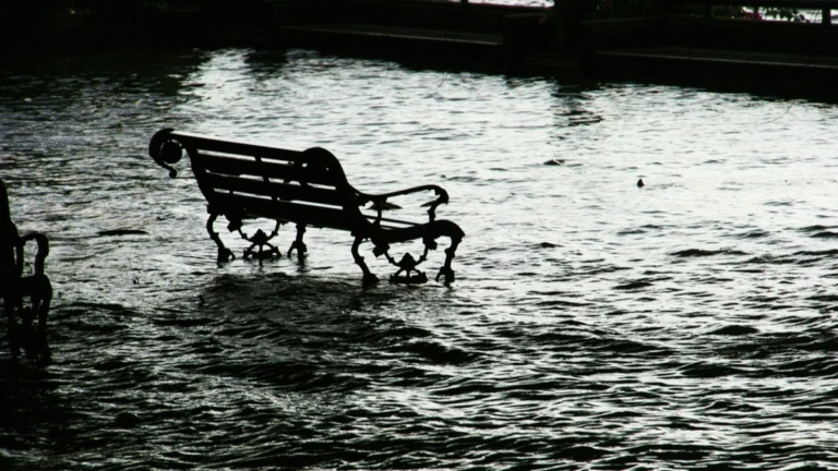 En parkbänk i högt vatten vid översvämning